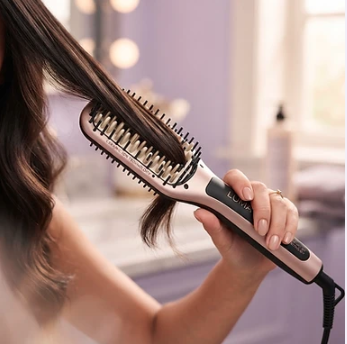 Mujer usando un cepillo alaciador sobre un mechón de cabello